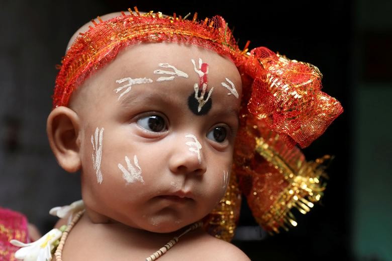 A child dressed as Hindu Lord Krishna accompanies his family for prayers during Janmashtami, or the birth anniversary of Lord Krishna, at a temple, in Kolkata, India. REUTERS/Rupak De Chowdhuri  